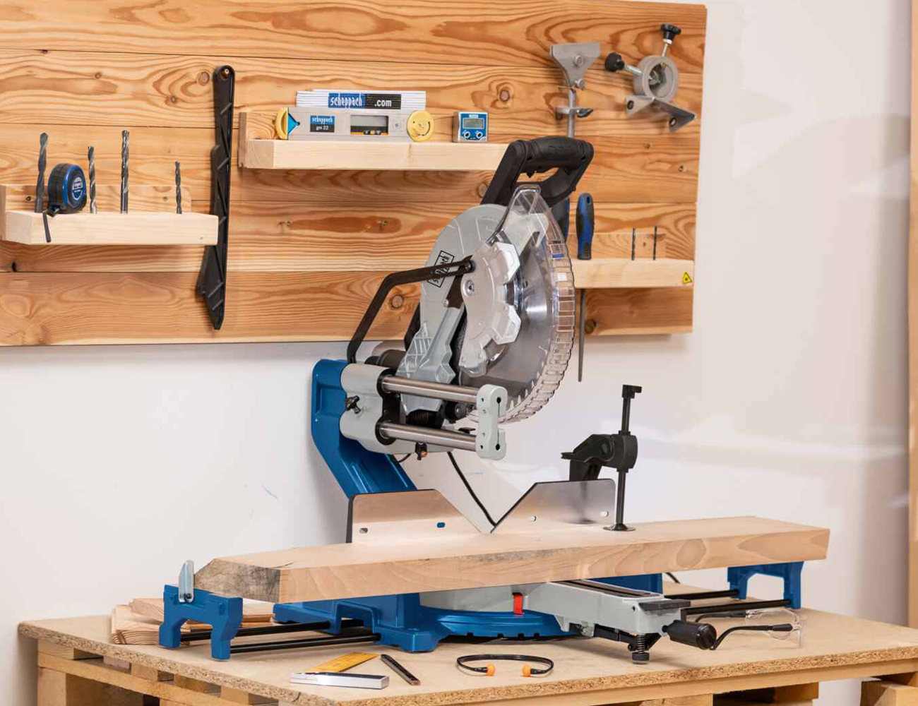 Scheppach-Kapp- und Gehrungssäge auf einem Holztisch. Im Hintergrund sind verschiedene Werkzeuge an einer Holzwand montiert.