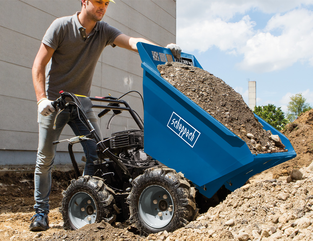 Ein Mann bedient einen Scheppach-Dumper mit Erde beladen. Der Dumper hat eine Tragfähigkeit von 300 kg.