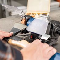 Doppelschleifer HG35 von Scheppach im Einsatz. Ein Werkstück wird mit einer Schleifscheibe bearbeitet. Die Maschine ist auf einem Tisch montiert.