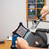 Nass-Schleifsystem TIGER 7000S Homekit Scheppach mit Schleifstein und Winkellehre. Ein Mann bedient das Gerät.