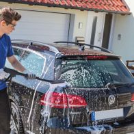Ein Mann wäscht ein Auto mit einem Scheppach Elektro-Hochdruckreiniger. Der Hochdruckreiniger ist in Aktion zu sehen.