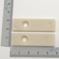 Ein Satz Führungsschienen mit vier Teilen, jeweils mit zwei Löchern. Die Teile sind etwa 5 cm lang und 2 cm breit. Die Schienen sind neben einem Lineal mit Zentimeter- und Millimeterskala platziert.