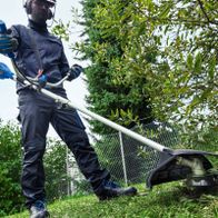 Arbeitsposition eines Bedieners mit Akku-Freischneider beim Schneiden von Pflanzen