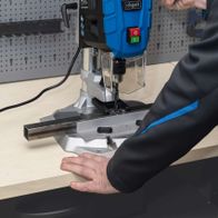 Scheppach bench pillar drill DP55 with digital speed display. A worker is operating the machine set to 580 RPM.