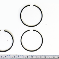 Kolbenringsatz mit drei Ringen, von oben fotografiert. Ein Ring ist in zwei Teile geteilt.