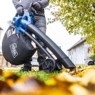 Person beim Einsatz eines Scheppach-Akku-Laubsaugers mit integriertem Bläser, Fokus auf die Handhabung und das Design des Geräts.