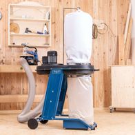 Absauganlage HD12 Scheppach mit Auffangbehälter und Schlauch, Werkbank mit Werkzeugen im Hintergrund.