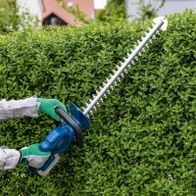 Person beim Schneiden mit Akku-Heckenschere, Fokus auf Handhabung und Einsatz im Heckenpflege