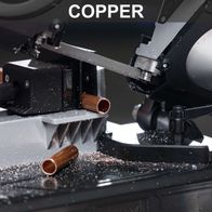 Band saw processing a copper tube, showing worn-out band with metal worktable and integrated LED lighting