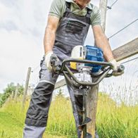 Mann betreibt Scheppach Erdbohrer mit Handgriff, Bohrer im Einsatz auf offener Fläche