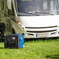 Ein Mann sitzt vor einem Wohnmobil und arbeitet auf einem Laptop. Vor ihm steht ein Scheppach Inverter SG3400i auf dem Rasen.