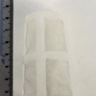 Ein Kraftstofffilter mit zwei quadratischen Filtern, daneben eine Messskala zur Größenbestimmung.