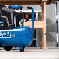 Scheppach HC30ox air compressor, 24L tank, 200L/min, 1.5HP, 230V, oil-free and low-maintenance. Side view of the compressor on a wooden shelf.