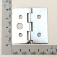 Ein Scharnier mit vier Löchern und einem zentralen Gelenk, von oben fotografiert. Das Scharnier hat eine quadratische Form und ist neben einem Lineal mit Zentimeter- und Millimeterskala platziert.