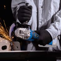 Werkzeug mit Akku-Winkelschleifer, Schutzhandschuh und Metallarbeitsstück mit Schleifspaß