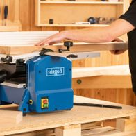 Abricht- & Dickenhobelmaschine HMS1070 Scheppach, 1500W, Hobelbreite 254mm, Höhe 120mm. Person bedient die Maschine in einer Werkstatt.