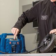 Person bedient einen Kompressor Airforce 5 von Scheppach. Der Kompressor hat ein LCD-Display und einen Reifen in der Hand.