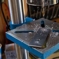 Bench drill DP19Vario by Scheppach in use. The drill bit is working on a metal piece on the worktable.