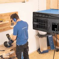 Luftreiniger HDA-14 von Scheppach, der an der Decke aufgehängt ist und von einem Arbeiter in einer Werkstatt verwendet wird.