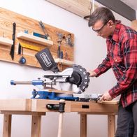 Mann beim Arbeiten mit einer Kappzugsäge von Scheppach in Werkstattumgebung