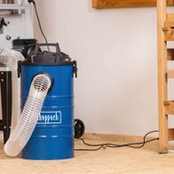 Dust Extractor DC100 by Scheppach with blue barrel and hose connection. The unit includes a 6-piece adapter set and has a metal container with a 65-litre capacity. The connection is 100 mm in diameter.