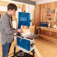 Person beim Arbeiten mit einer Scheppach-Bandsäge in einem Holzwerkstatt-Setting