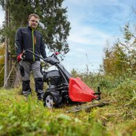 Mann mit Scheppach-Balkenmäher auf dem Gelände, der mit einem roten Sammelbeutel arbeitet