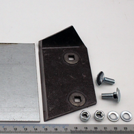 Ein Messinggegenmesser mit zwei Metallplatten und Befestigungsschrauben. Die Teile sind auf einem Lineal mit Millimeter- und Zentimeterangaben platziert.