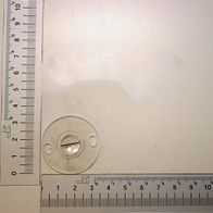 Ein Lineal mit Millimeter- und Zentimeter-Einteilung. Im Hintergrund ist ein runder Gegenstand mit einer Linse zu sehen.