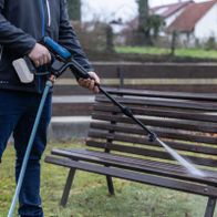 Person beim Reinigen mit Scheppach Hochdruckreiniger, Schlauch in Aktion