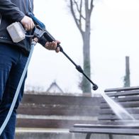 Person beim Reinigen mit Akku-Druckreiniger, Schlauch in Gebrauch