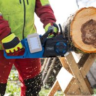 Scheppach Akku-Kettensäge mit Akku und Schnittvorrichtung, Detailansicht mit Arbeitsgeräuschen und Materialabrieb