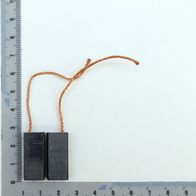 Zwei Kohlebürsten mit Kupferdrahtanschlüssen, daneben ein Lineal zur Größenveranschaulichung.