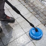 Hochdruckreiniger HCE2000 Scheppach mit rotierender Bürste auf Steinboden. Die Bürste ist an einem schwarzen Schlauch befestigt.