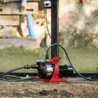 Gartenpumpe GP1400JET von Scheppach mit 1300W Leistung, 6000L/h Fördermenge, 4,8bar Förderdruck und max. 8m Saughöhe. Gezeigt von der Seite mit angeschlossenem Schlauch.