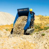 Kettendumper DP5000 Scheppach mit gelbem Helm tragender Person. Der Dumper ist mit Steinen beladen und fährt auf einem Kiesweg.