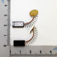 Kohlebürstensatz 5,3x5,3x10,5 (1 Satz = 2 Stück) auf einem Lineal. Die Kohlebürsten sind mit Spiralfedern verbunden.