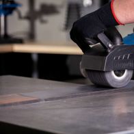 Scheppach Siliziumkarbidbürste im Einsatz an einer MRS1300 Satiniermaschine. Die Bürste wird von einer Person mit Schutzhandschuhen geführt.