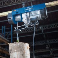 Elektrischer Seilzug HRS400 von Scheppach mit 400 kg Tragfähigkeit. Gezeigt wird der Seilzug mit einem Holzklotz als Last.