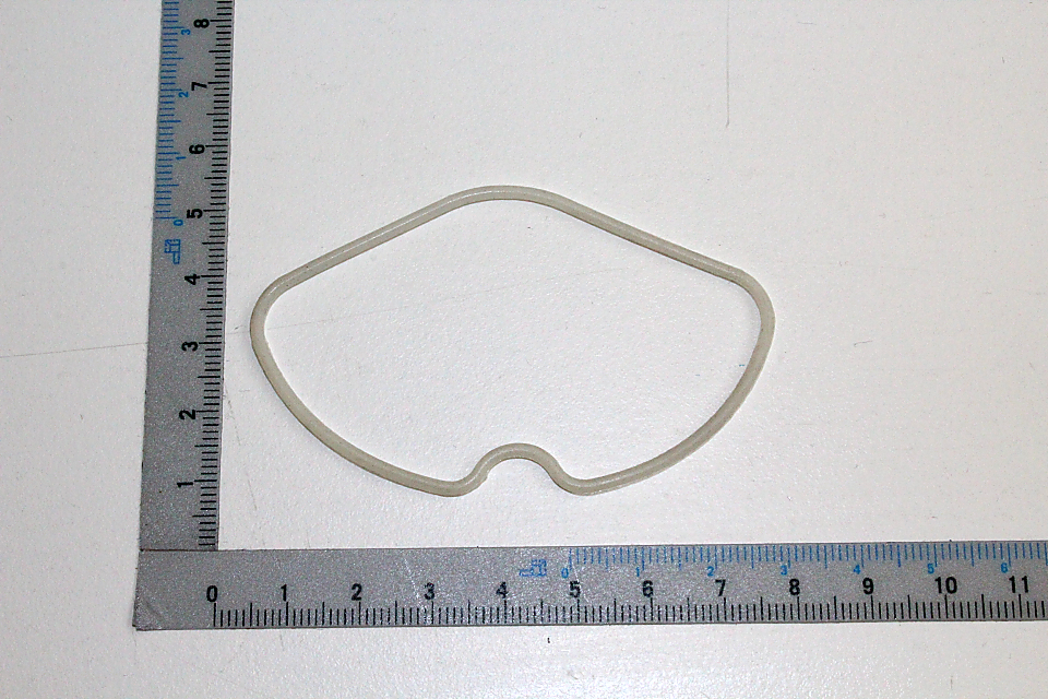 Zylinderkopfdichtung, oval geformt, neben einem Lineal zur Größenveranschaulichung.