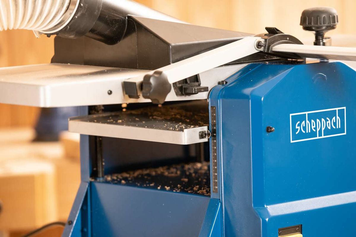 Abricht- & Dickenhobelmaschine HMS1070 Scheppach, Detailansicht von vorne mit Messskala und Staubabsaugung.