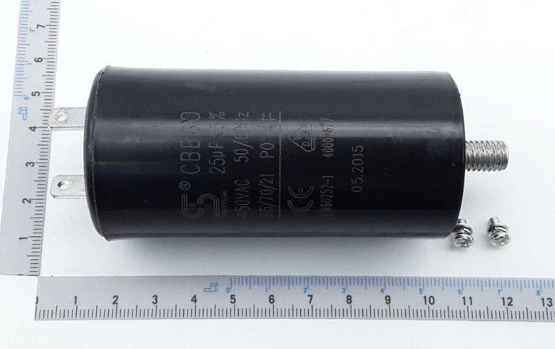 Kondensator 25µF / 450V von Scheppach, von der Seite fotografiert. Der Kondensator ist 12 cm lang und hat einen Durchmesser von 5 cm. Im Hintergrund sind zwei Muttern zu sehen.