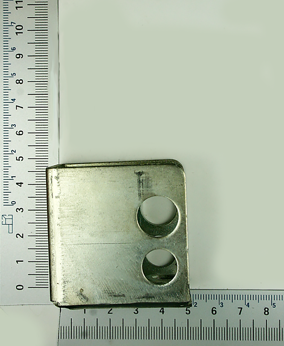 Metallplatte mit zwei runden Öffnungen, von oben fotografiert. Maße: 5 cm x 5 cm.