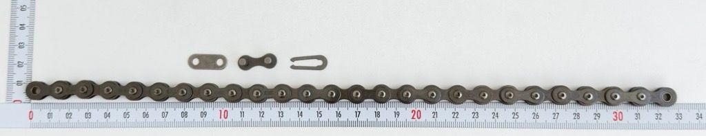 Eine Rollenkette mit Verschluss, 1/2"x1/8" - 26 Glieder mit Verschlussglied, von Scheppach. Die Kette liegt auf einem Lineal und ist von vorne fotografiert.