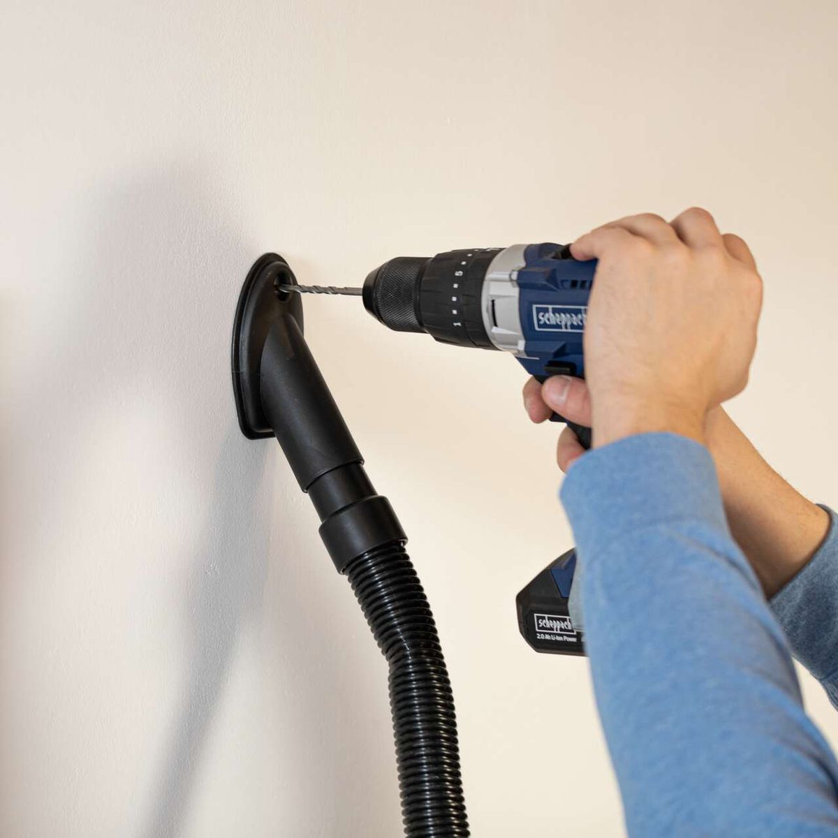 Absauganlage HD2P Scheppach mit 1250W Leistung, Kunststoffgehäuse, inkl. Bohr-Absaugdüse und Saug-Blasdüse. Die Absauganlage ist mit einem Scheppach-Bohrer verbunden und saugt Staub direkt an der Arbeitsstelle ab.