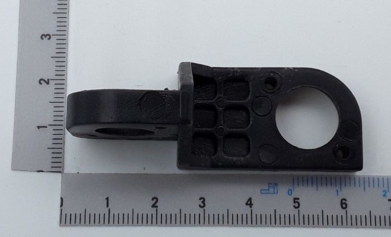 Ein schwarzes Gelenkteil mit Loch und mehreren Vertiefungen, von der Seite betrachtet.