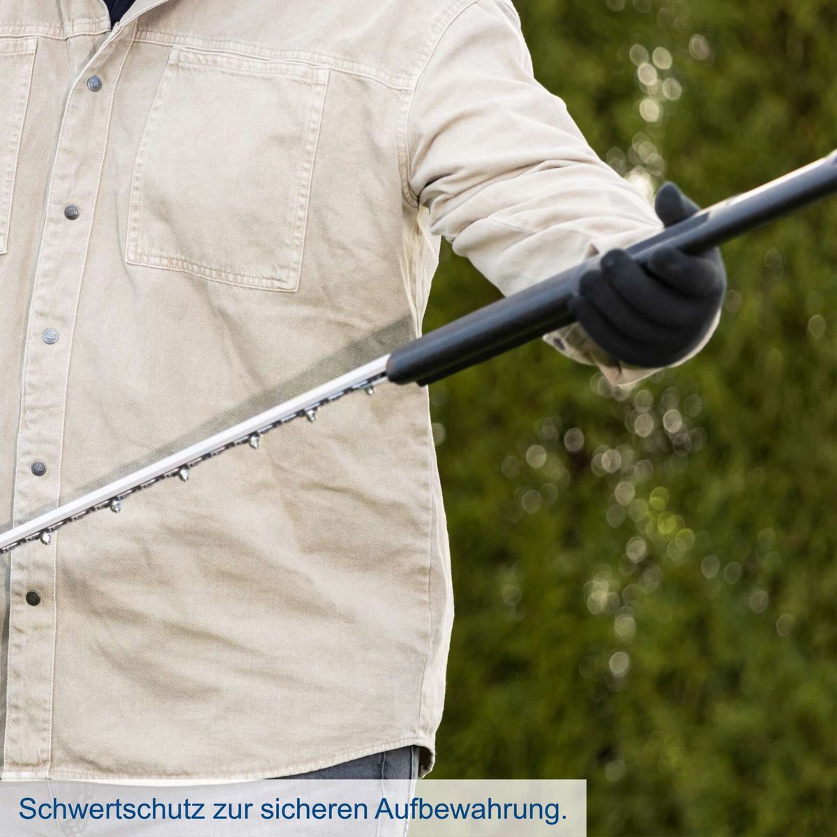 Person mit Akku-Heckenschere, Schutzausrüstung für sicheres Arbeiten gezeigt