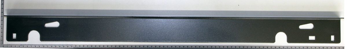 Ein schwarzer Winkelanschlag mit Aussparungen, gezeigt von oben auf einem Lineal.