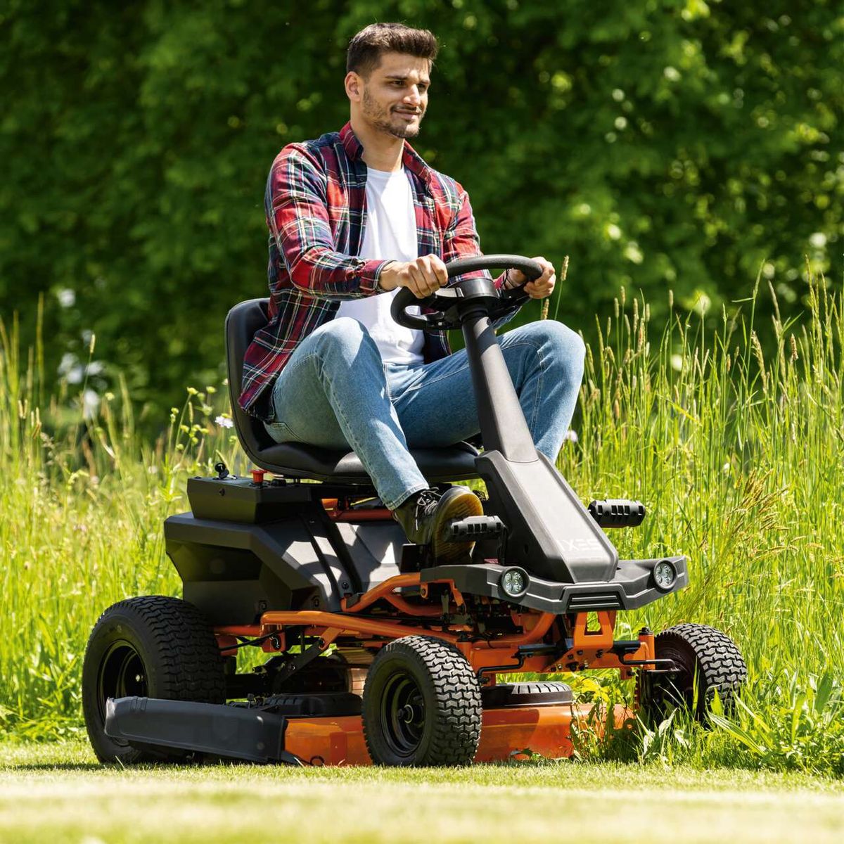 Der Akku-Aufsitzrasenmäher IX-ERT-920E IXES mit 48V Motor, 92cm Schnittbreite, 120cm Wendekreis und 7-stufiger Schnitthöhenverstellung. Der Mann sitzt auf dem Rasenmäher und lächelt.