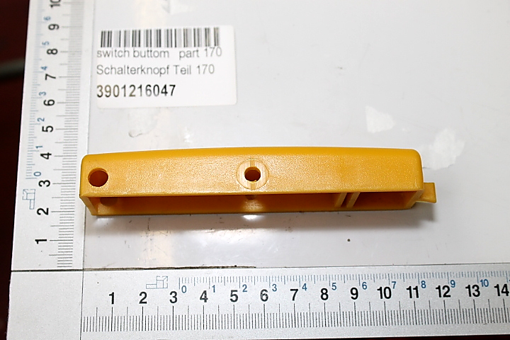 Ein gelber Schalterknopf mit zwei Löchern, Teilnummer 170, Artikelnummer 3901216047. Der Schalterknopf liegt auf einem Lineal und ist von der Seite zu sehen.